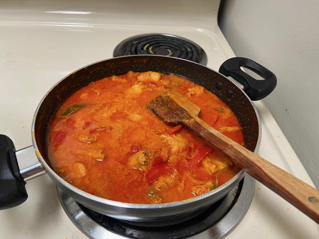 A large pan full of a deep red Thai chicken curry.